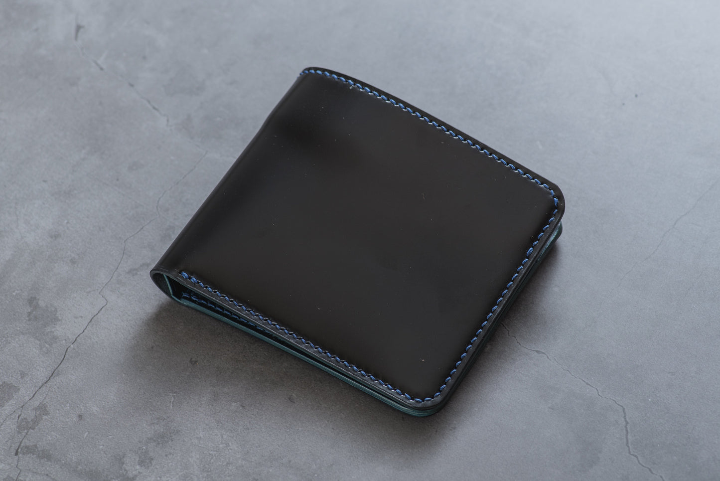 A black leather bifold wallet with contrasting blue stitching