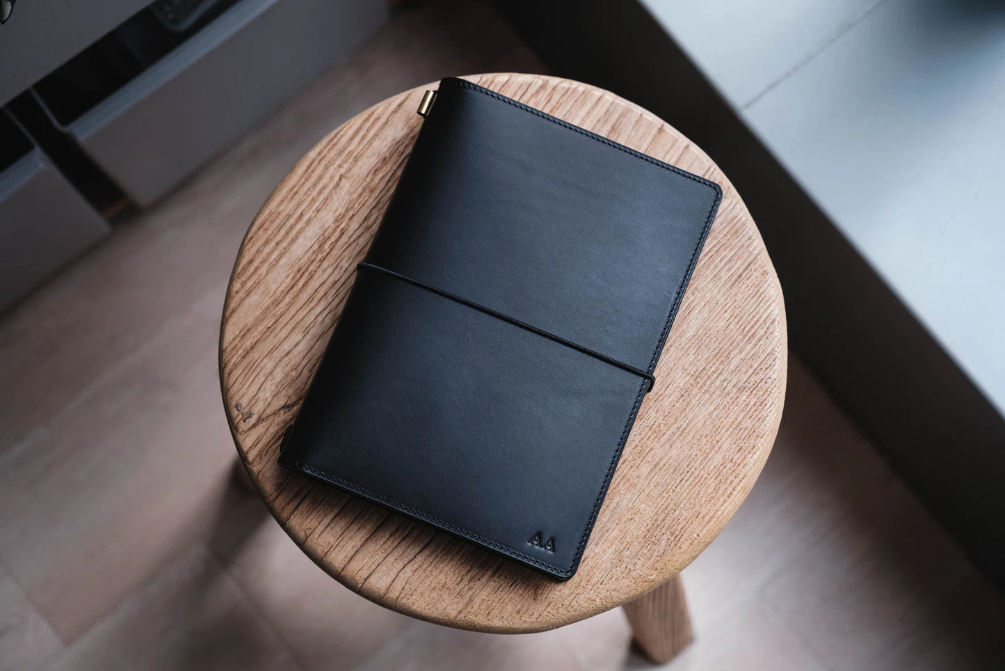 A black Stitched Buttero Leather Traveler's Notebook and a elastic enclouse, displayed close