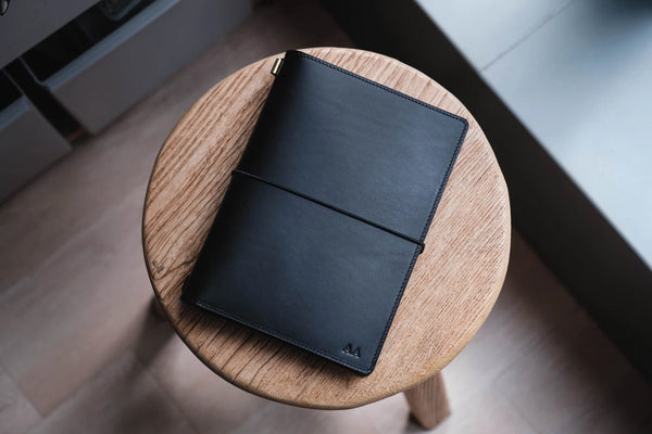 A black Stitched Buttero Leather Traveler's Notebook and a elastic enclouse, displayed close