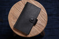 A black pebbled leather traveler's notebook with a strap closure, displayed closed