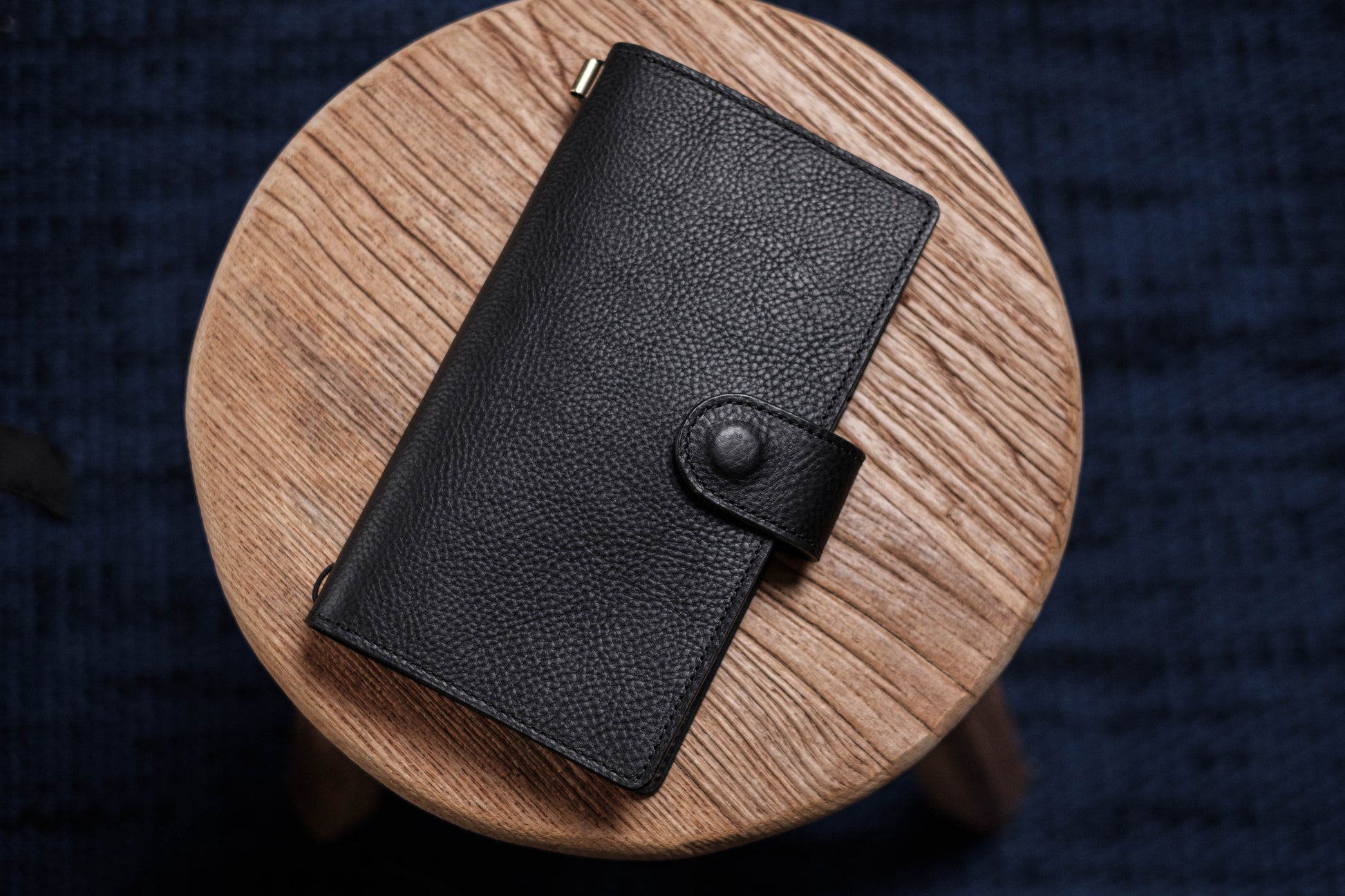 A black pebbled leather traveler's notebook with a strap closure, displayed closed