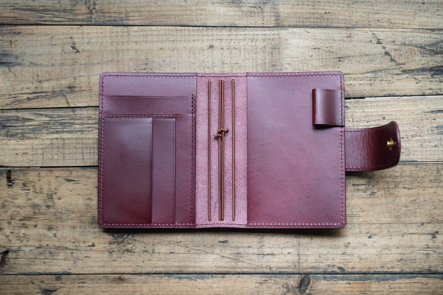 A burgundy Stitched Buttero Leather Traveler's Notebook with Card Slots and elastic strands and pen loop, displayed open