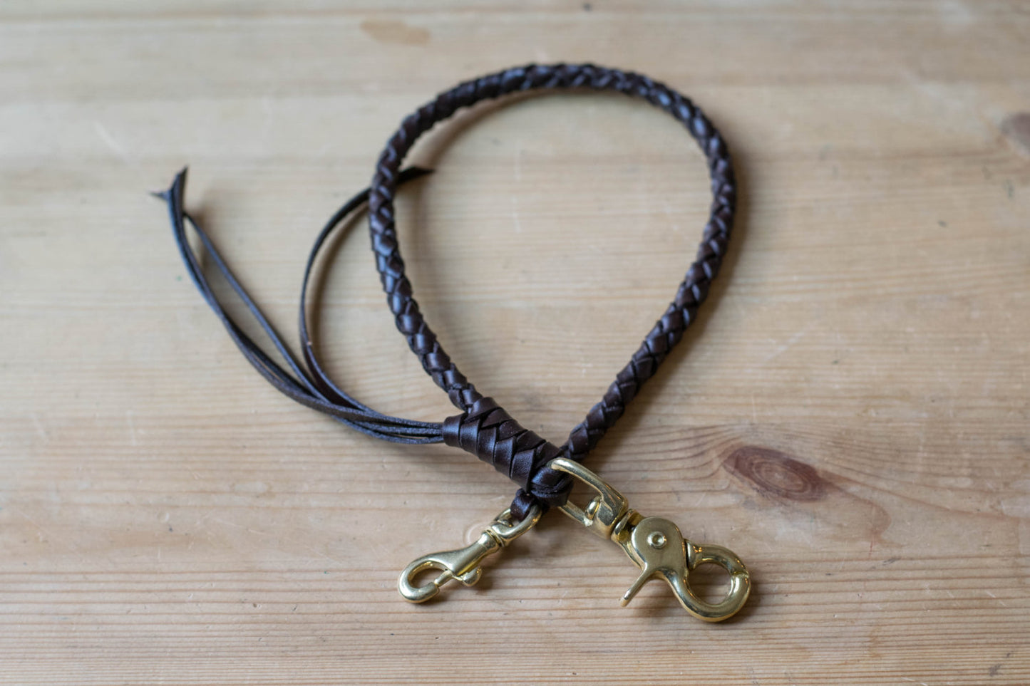 A round braid dark brown vegetable-tanned leather wallet rope with a solid brass trigger snap 