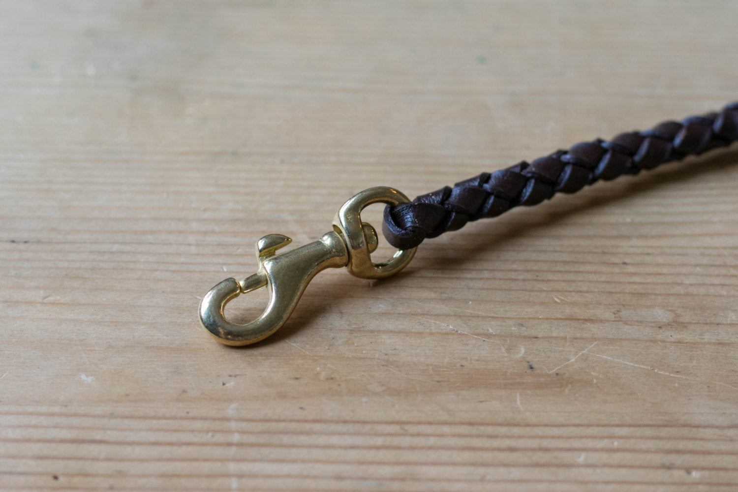 A round braid dark brown vegetable-tanned leather wallet rope with a solid brass trigger snap - close up for solid brass snap
