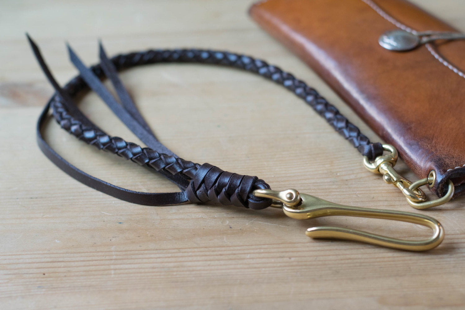 Brown braided leather strap with solid brass hardware attached on long wallet -lifestyle view
