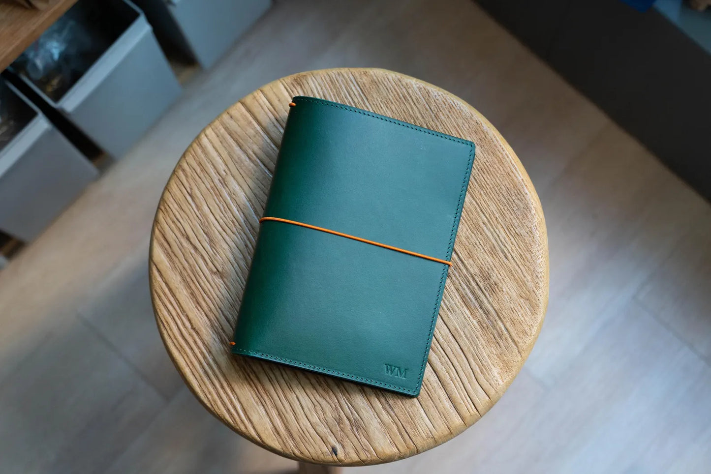 A green Stitched Buttero Leather Traveler's Notebook and a elastic enclouse, displayed close
