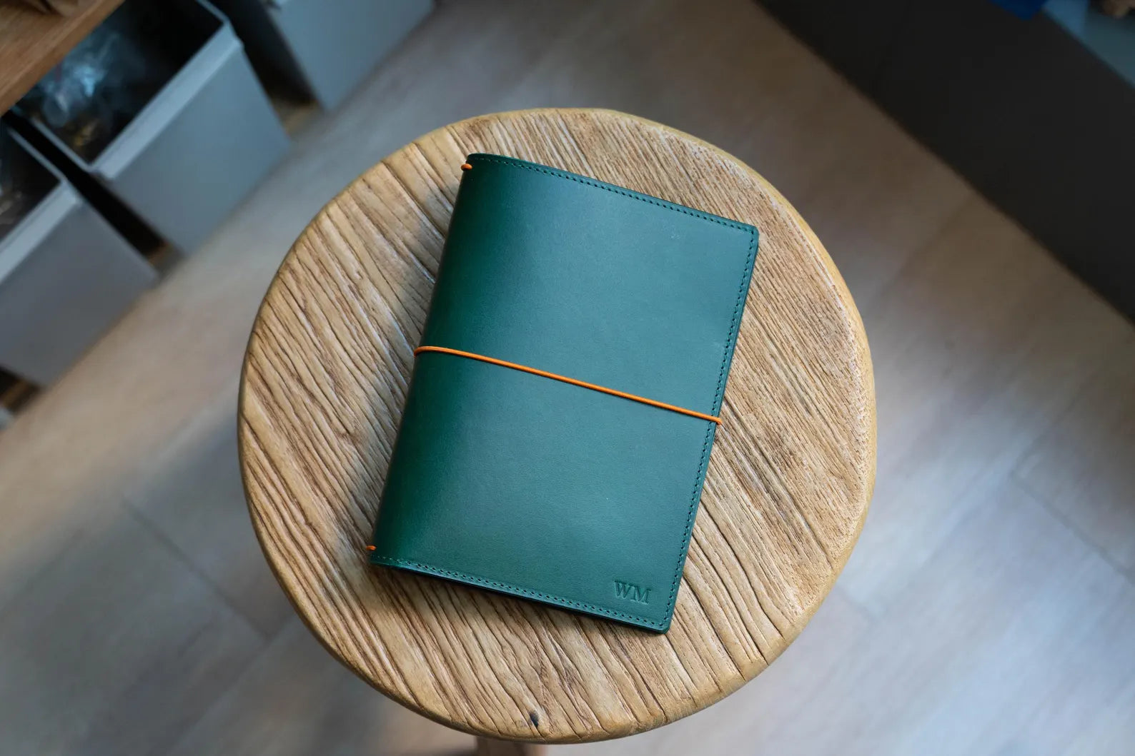 A green Stitched Buttero Leather Traveler's Notebook and a elastic enclouse, displayed close