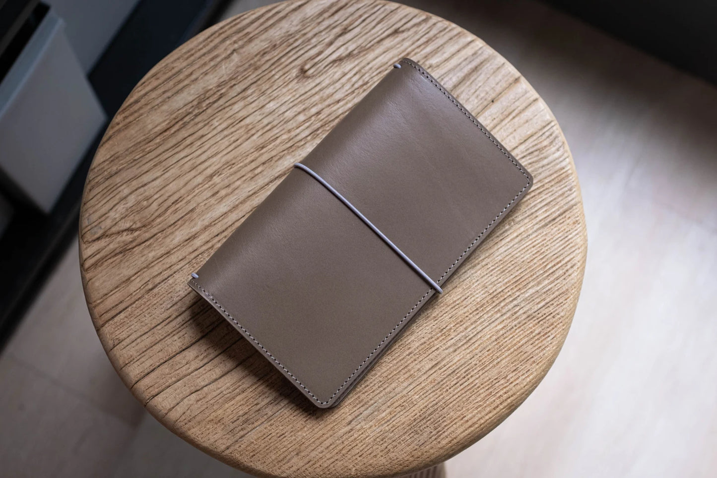 A khaki grey Stitched Buttero Leather Traveler's Notebook and a elastic enclouse, displayed close