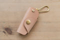 A natural buttero leather key case with brass hardware and a removable brass wire hook.