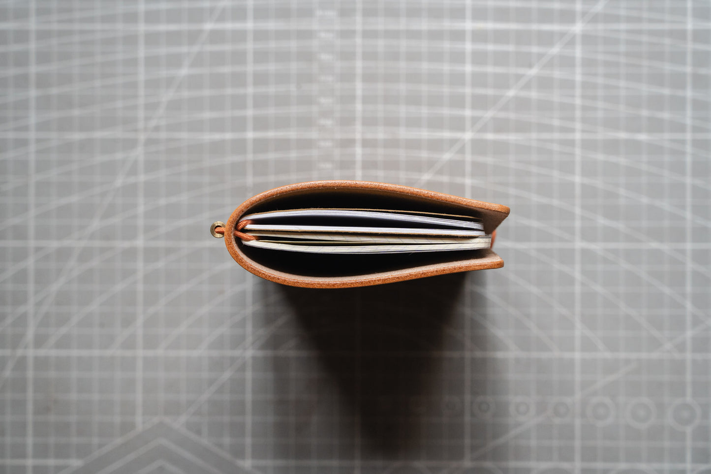 A top-down view of a slim undyed leather notebook or planner cover.