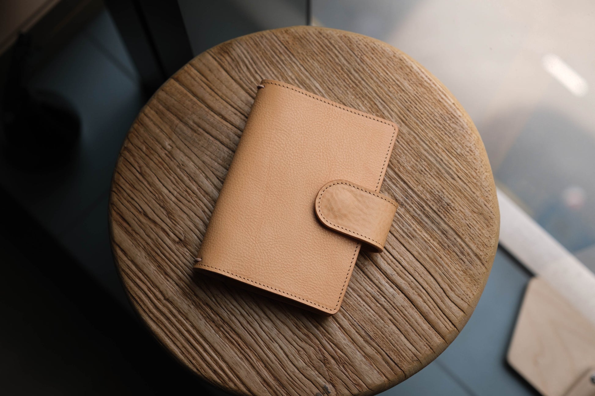 A natural pebbled leather traveler's notebook with a strap closure, displayed closed