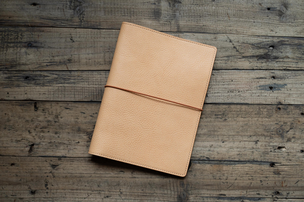 A natural b6 leather notebook cover with red elastic closure