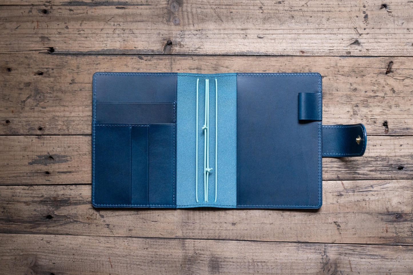 A navy blue Stitched Buttero Leather Traveler's Notebook with Card Slots and elastic strands and pen loop, displayed open