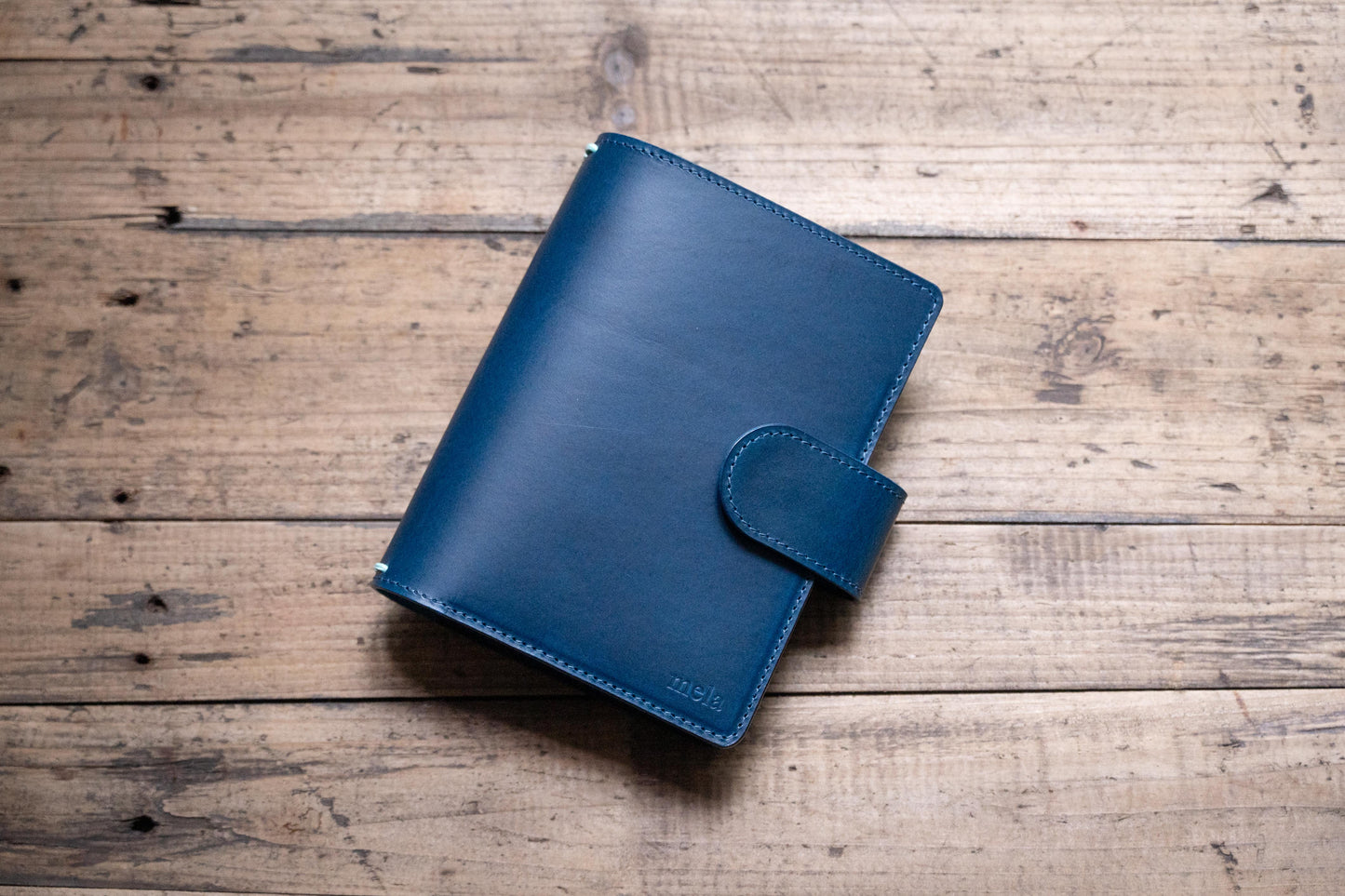 A navy blue Stitched Buttero Leather Traveler's Notebook with Card Slots and a  leather strap, displayed close