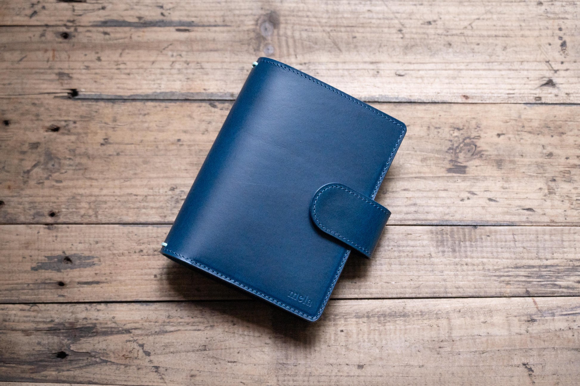 A navy blue Stitched Buttero Leather Traveler's Notebook with Card Slots and a  leather strap, displayed close