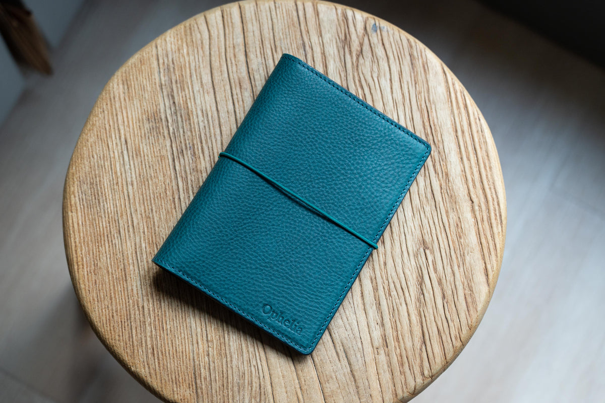 A navy blue leather notebook cover with a blue elastic closure.