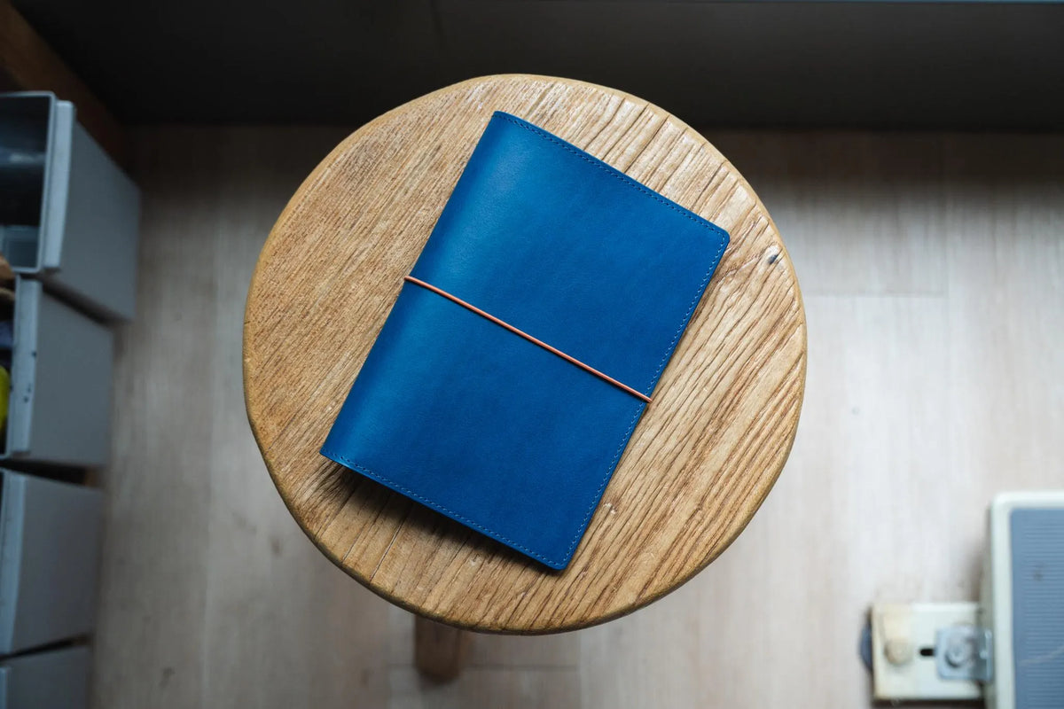 A navy blue leather journal with a orange elastic band. 