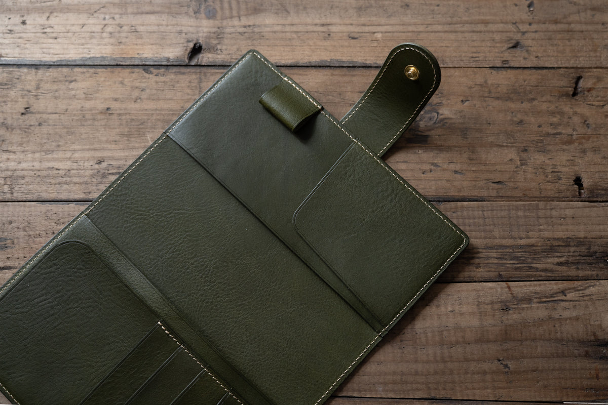 A olive green pebbled leather notebook folio cover with card slots and a snap closure, displayed open.