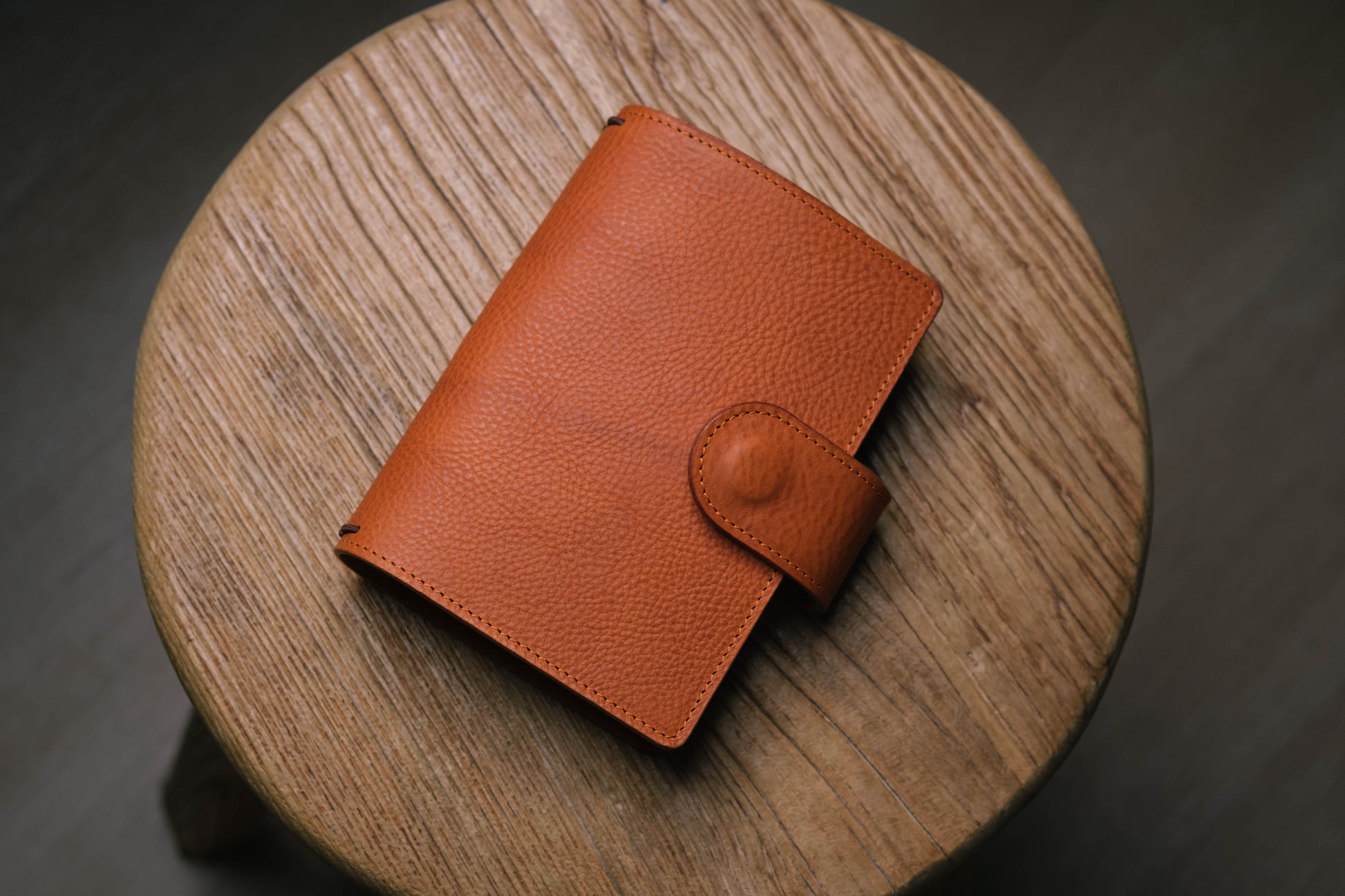 A orange brown pebbled leather traveler's notebook with a strap closure, displayed closed