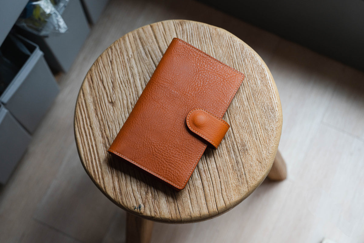 An orange-brown leather journal cover with a flap closure and a textured surface. 