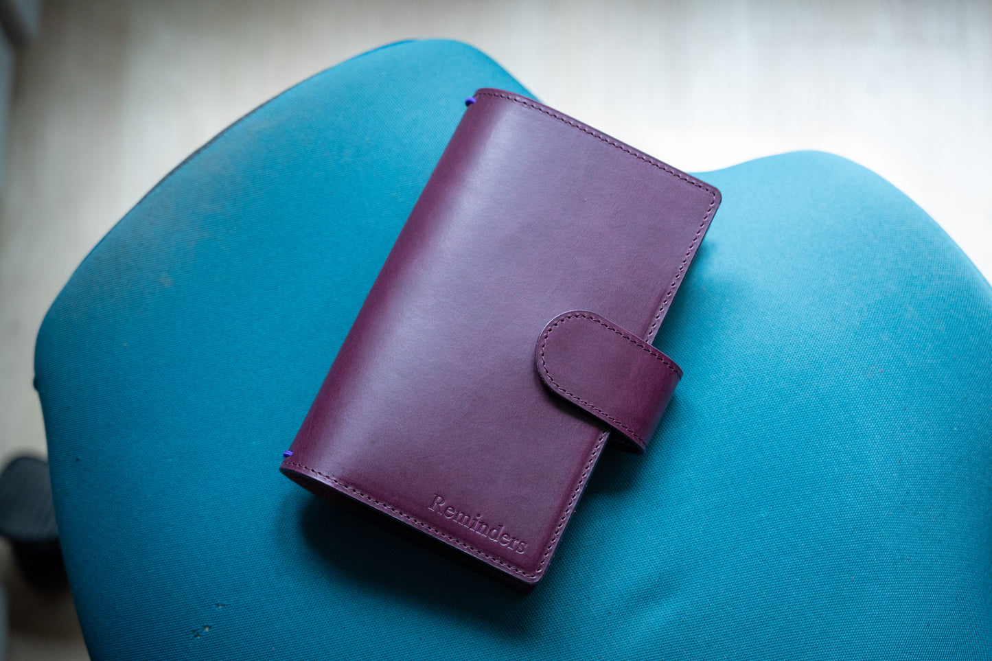 A burgundy Stitched Buttero Leather Traveler's Notebook with Card Slots and elastic strands and pen loop, displayed close