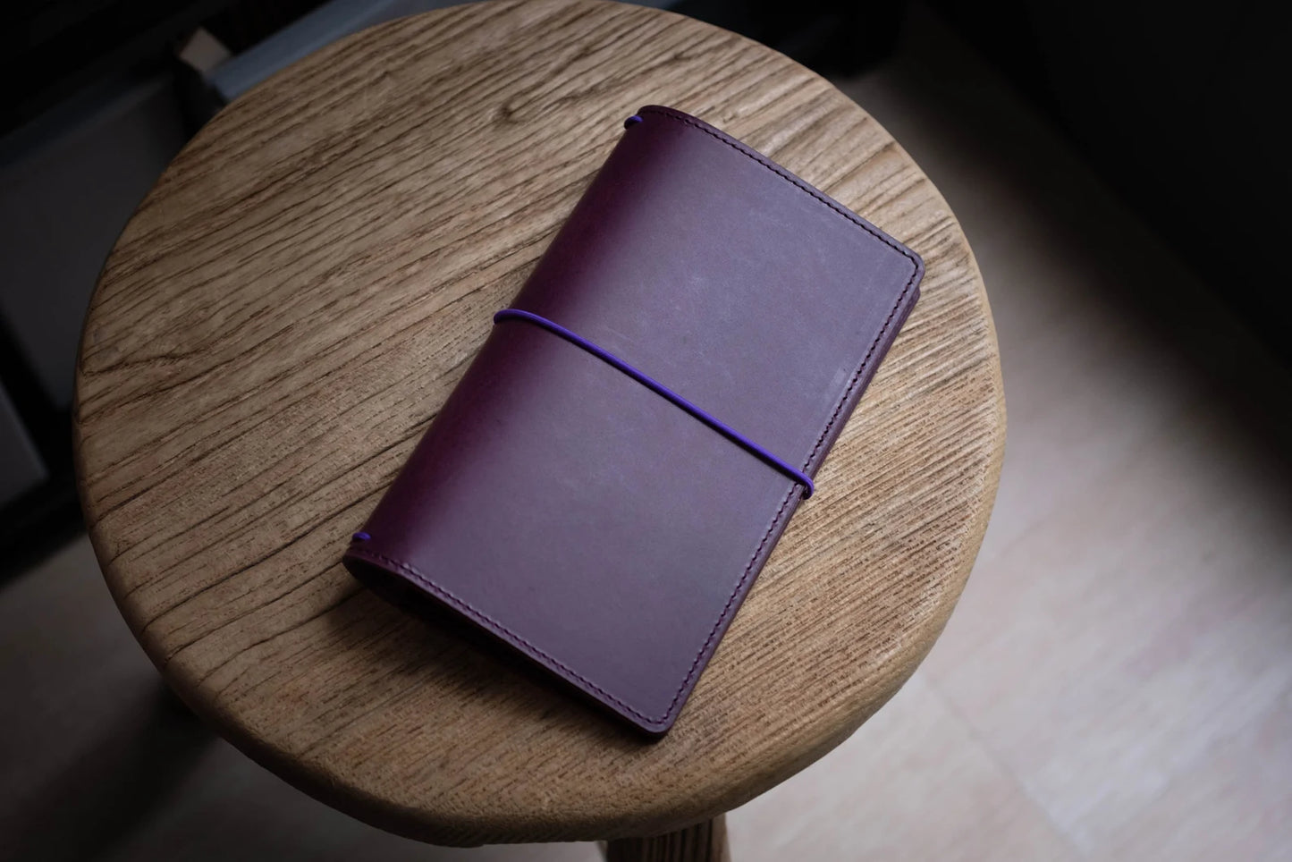 A purple Stitched Buttero Leather Traveler's Notebook and a elastic enclouse, displayed close