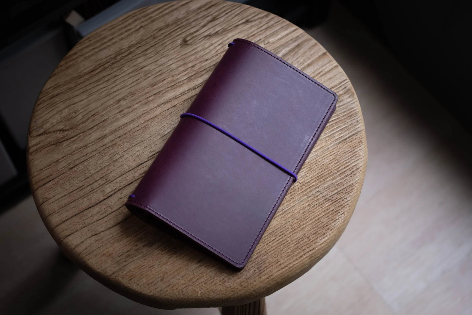 A purple Stitched Buttero Leather Traveler's Notebook and a elastic enclouse, displayed close