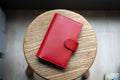 A red Stitched Buttero Leather Traveler's Notebook with Card Slots and a  leather strap, displayed close