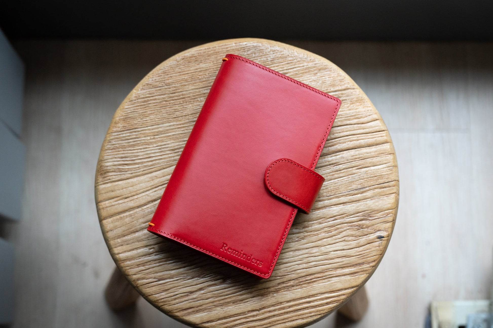 A red Stitched Buttero Leather Traveler's Notebook with Card Slots and a  leather strap, displayed close