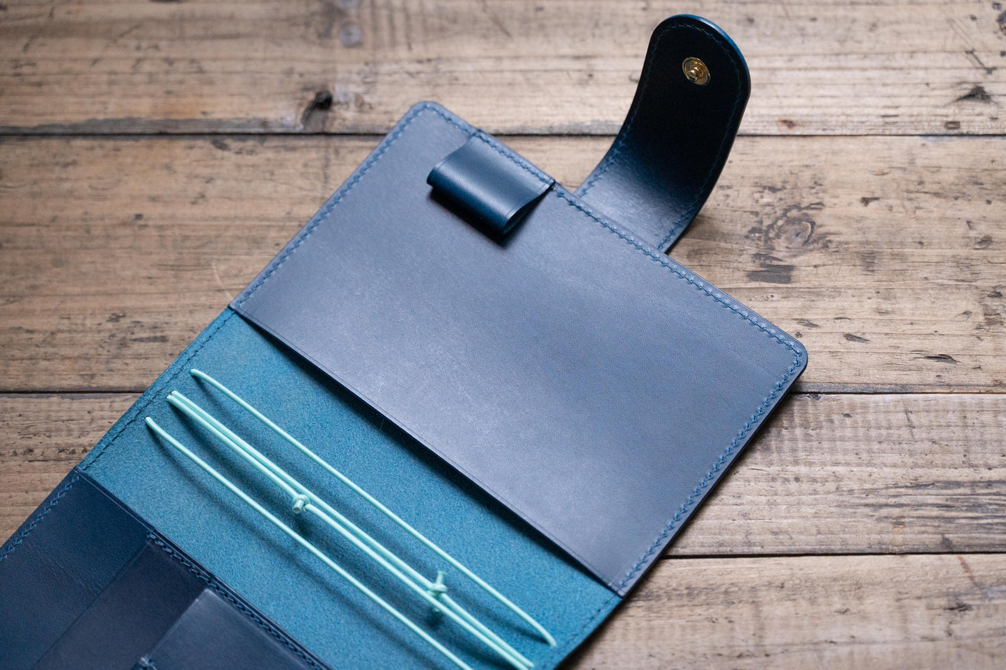 A navy blue Stitched Buttero Leather Traveler's Notebook with Card Slots and elastic strands and pen loop, displayed open, close up of inside right pocket