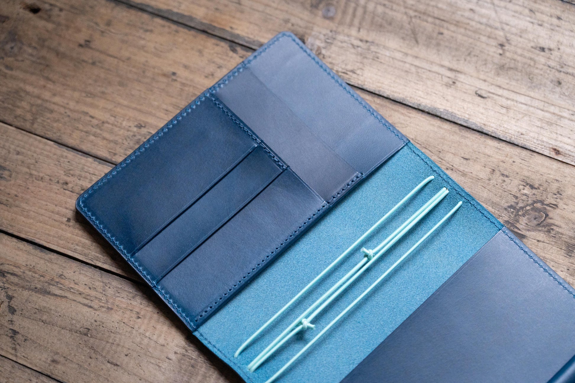 A navy blue Stitched Buttero Leather Traveler's Notebook with Card Slots and elastic strands and pen loop, displayed open, close up of inside left pocket
