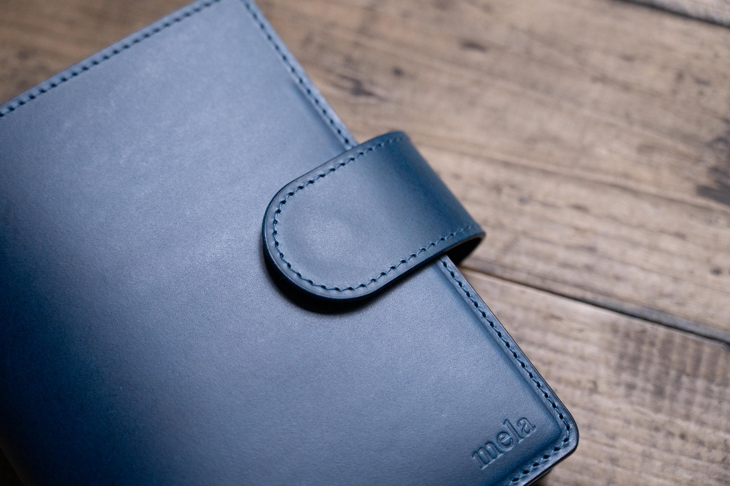 A navy blue Stitched Buttero Leather Traveler's Notebook with Card Slots and a  leather strap, close up of leather strap and stitching