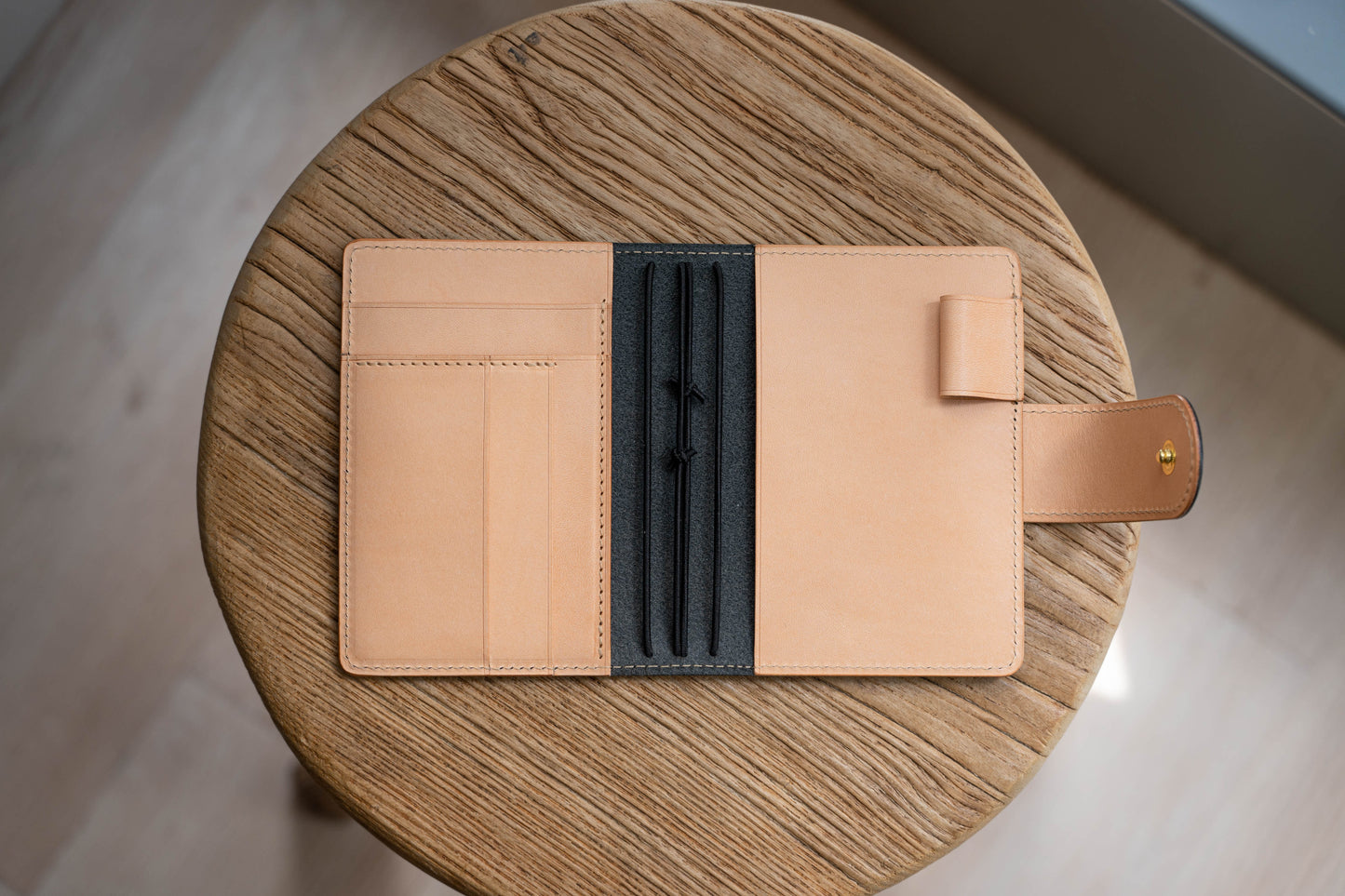 A black and natural two-tone leather traveler's notebook with card slots, displayed open
