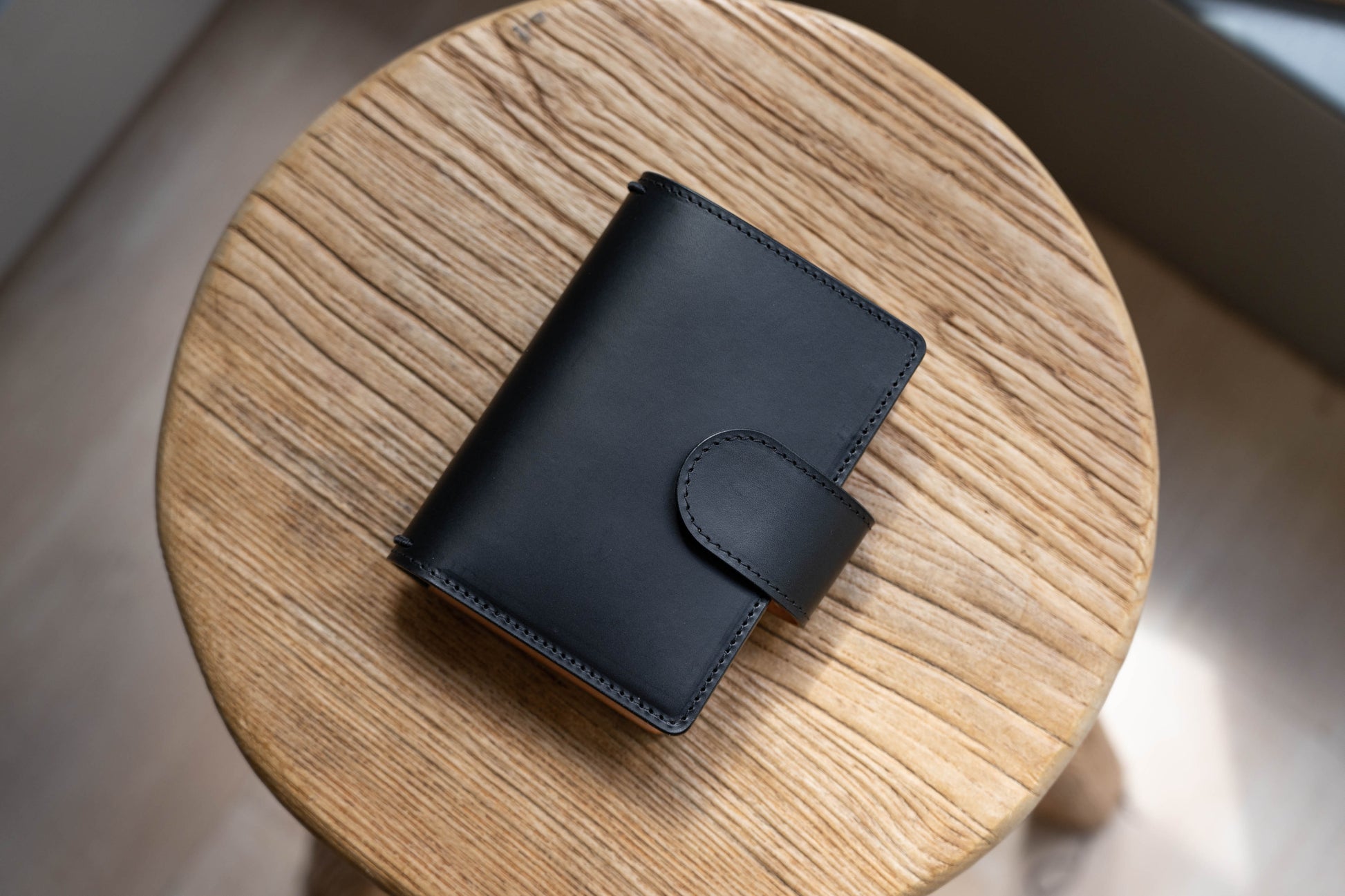 A black and natural two-tone leather traveler's notebook with card slots, displayed closed