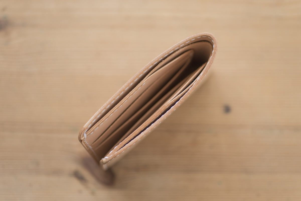 A natural leather wallet with multiple card slots and a billfold. The wallet is open and empty.