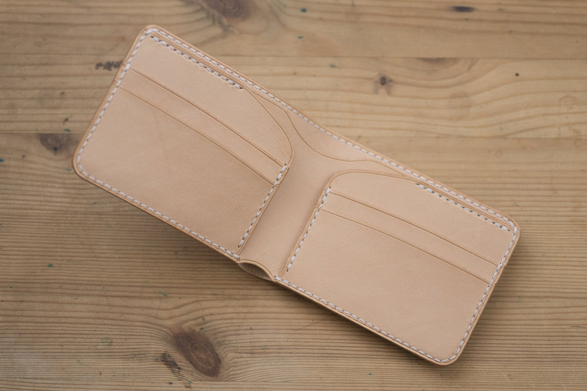 A natural leather wallet with white stitching. The wallet is folded open to reveal the interior, which has 4 card slots and a billfold.