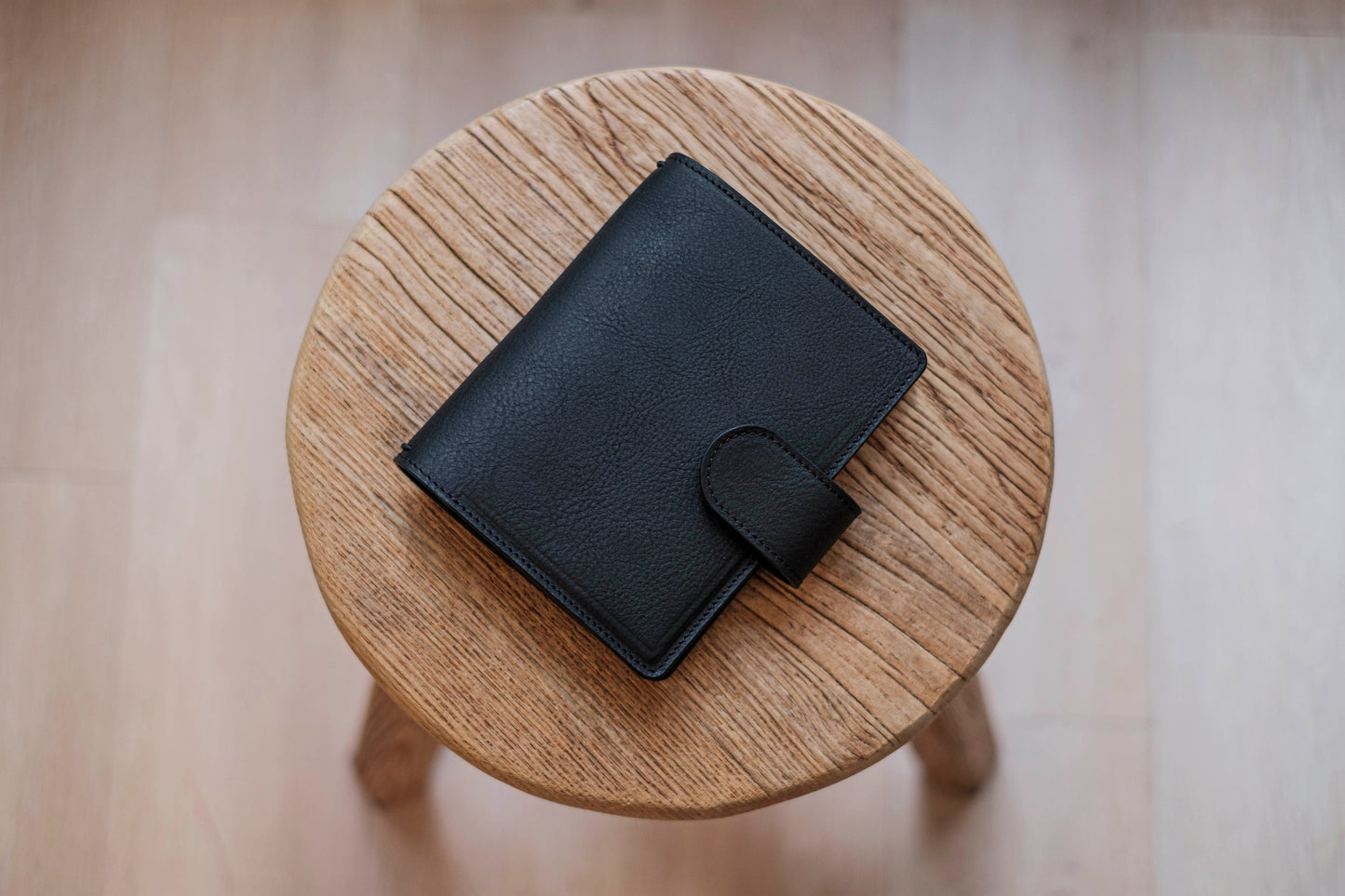 A black lined traveler's notebook with card slots and a leather strap, displayed close