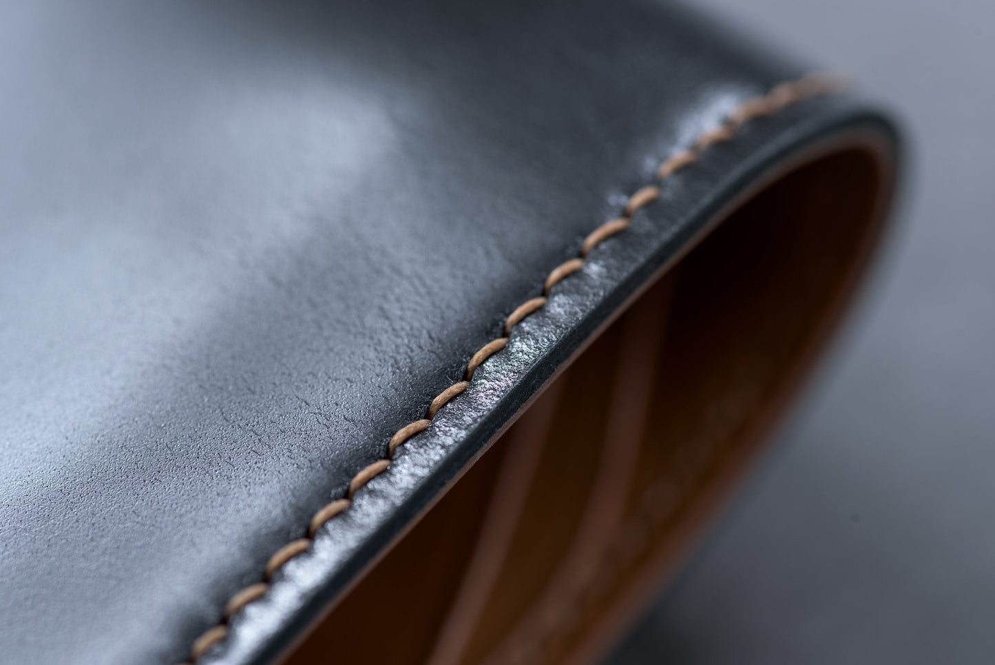 Close-up of a black leather wallet with a brown stitched edge.