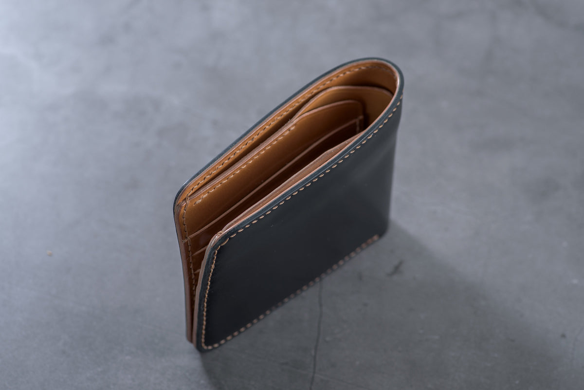A black leather wallet with a whisky leather interior. The wallet is folded in half and the interior is visible.
