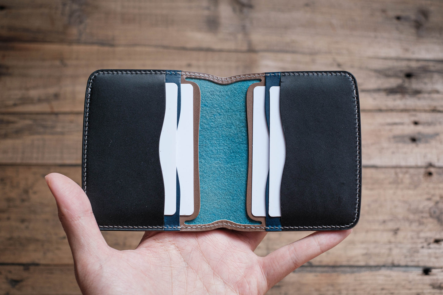 A black leather card holder with a blue leather interior and multiple card slots.