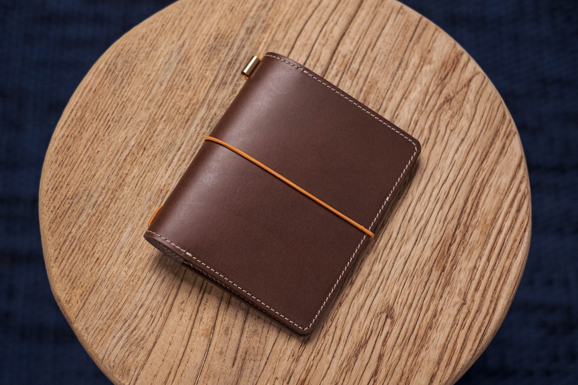A brown Stitched Buttero Leather Traveler's Notebook and a elastic enclouse, displayed close