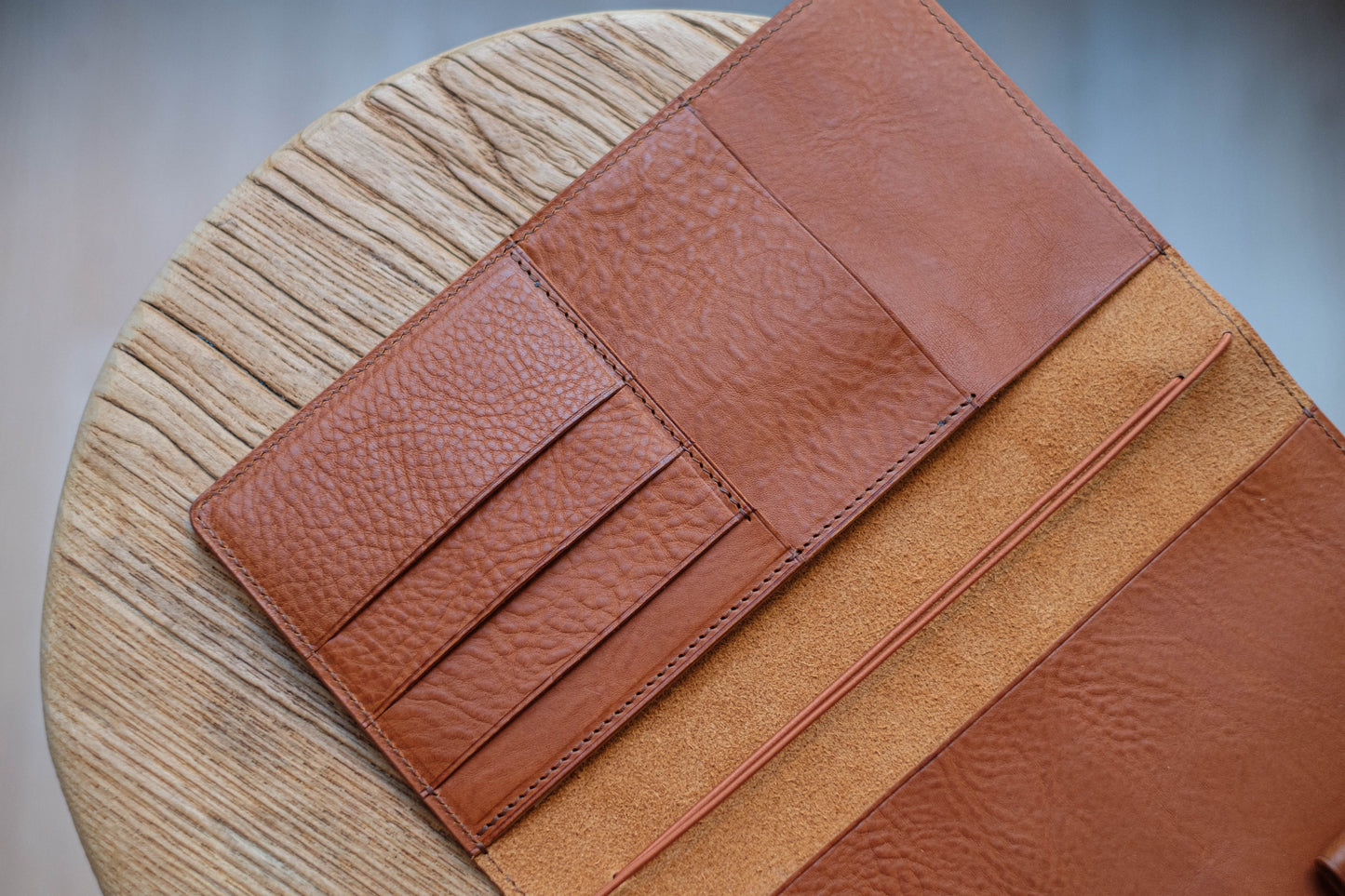 A brown leather traveler's notebook with card slots and a snap button closure, displayed open, close up of left card slots