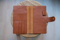A brown leather traveler's notebook with card slots and a snap button closure, displayed open