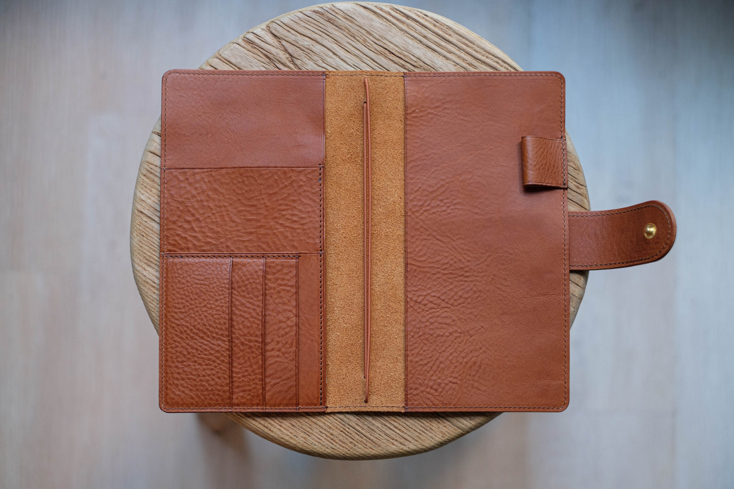 A brown leather traveler's notebook with card slots and a snap button closure, displayed open