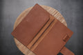 A brown pebbled leather traveler's notebook with a strap closure, displayed open