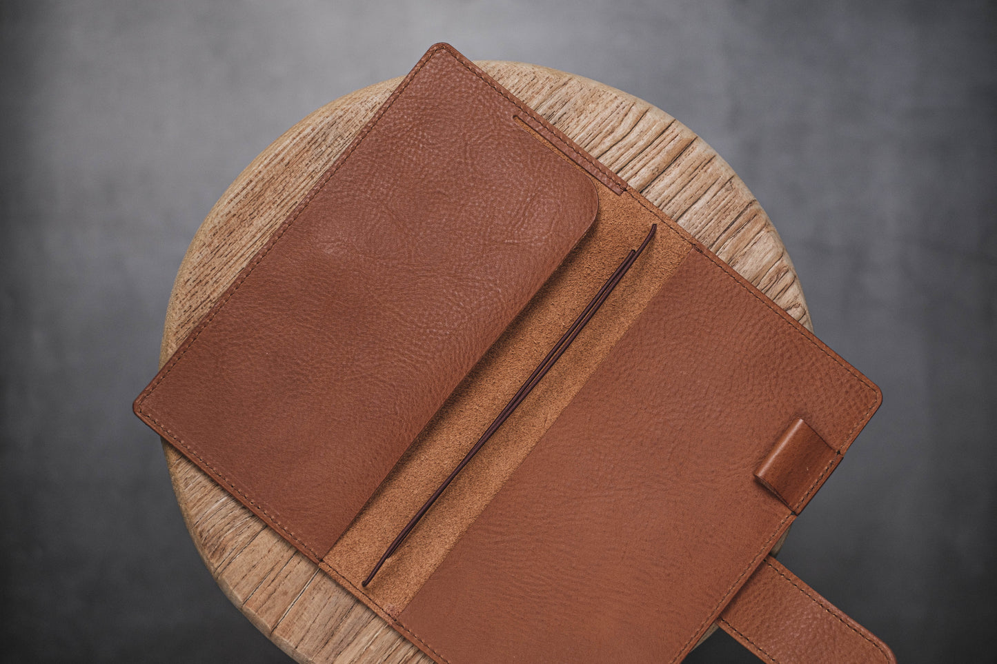 A brown pebbled leather traveler's notebook with a strap closure, displayed open