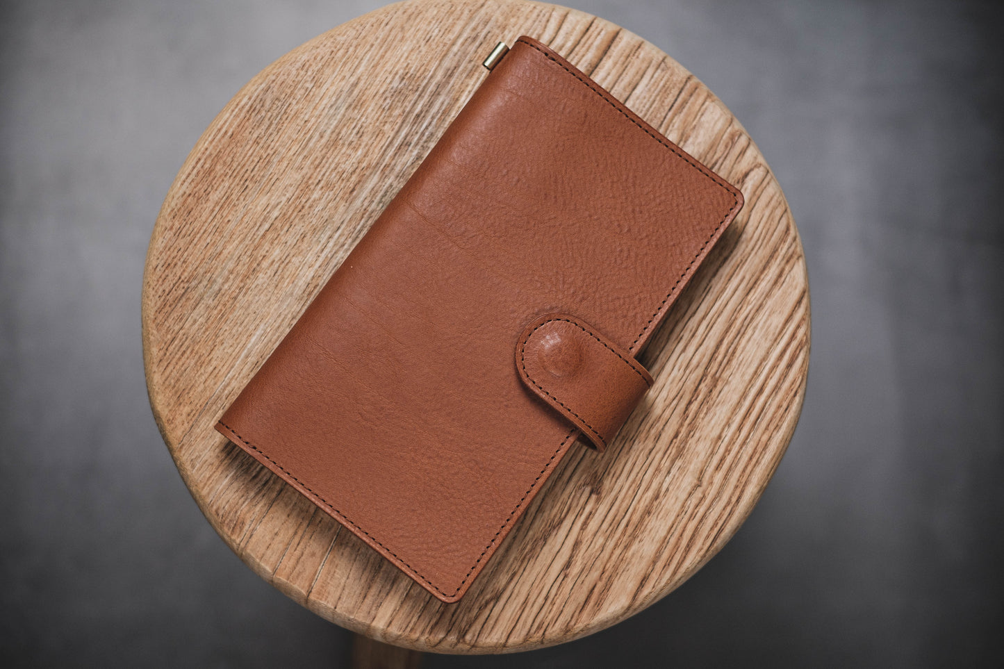 A brown pebbled leather traveler's notebook with a strap closure, displayed closed