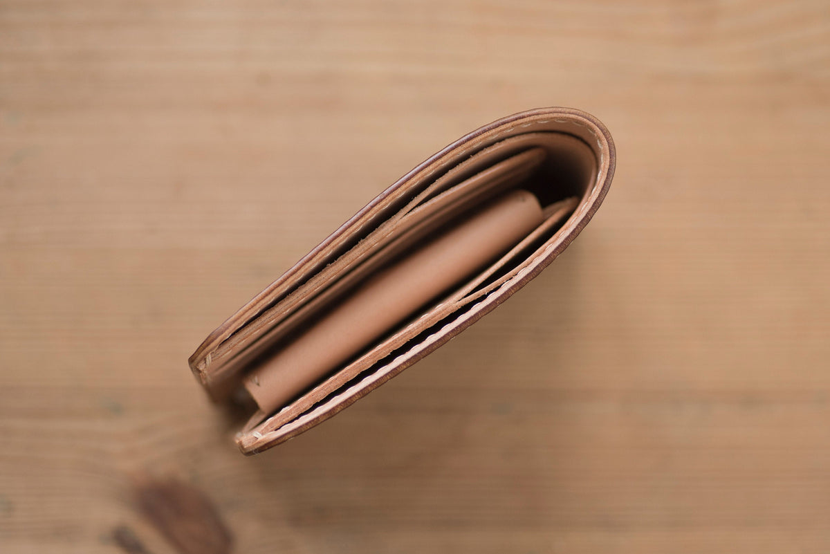 A brown leather wallet folded closed, showing the inside seams and stitching.