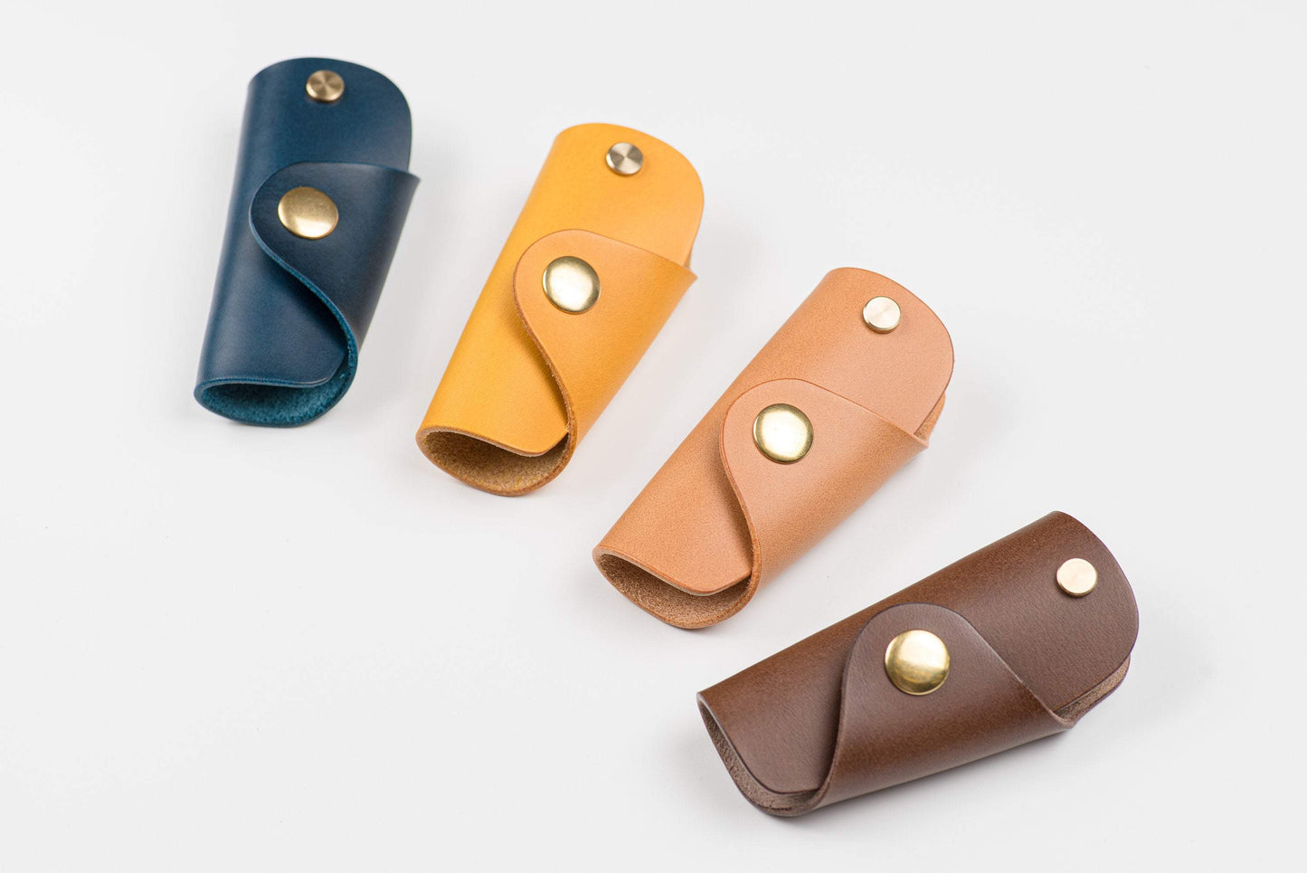 4 Buttero Leather Key Case in navy blue, mustard yellow, pink and brown color with brass hardware and a removable brass wire hook.