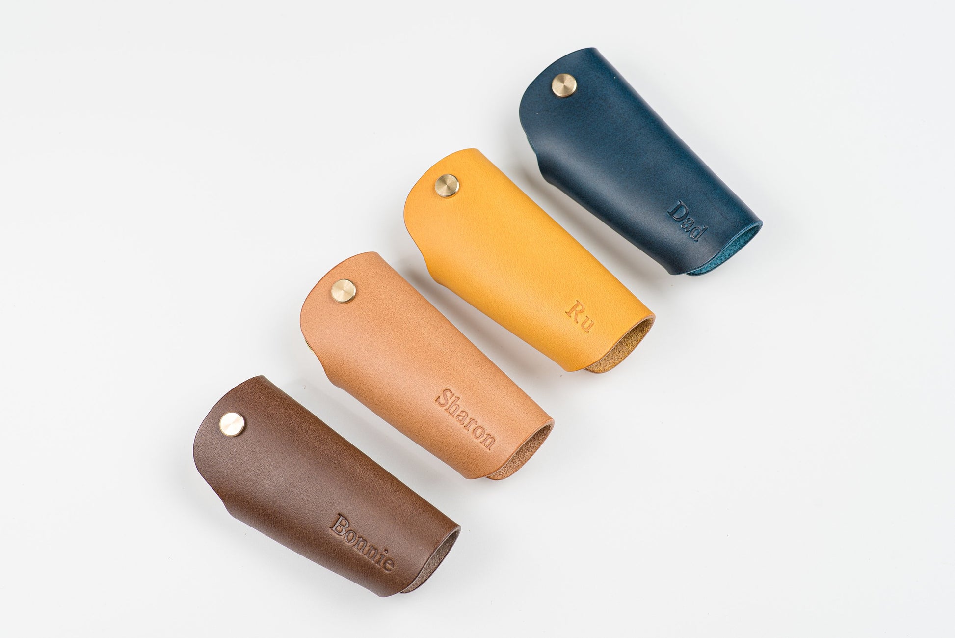 4 Buttero Leather Key Case in navy blue, mustard yellow, pink and brown color with brass hardware and a removable brass wire hook with monogram